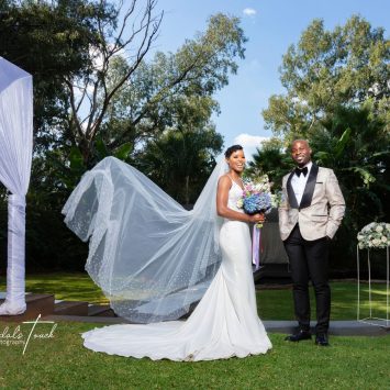 Bride and groom smile under a canopy at The Garden Venue wedding venue on a sunny day.